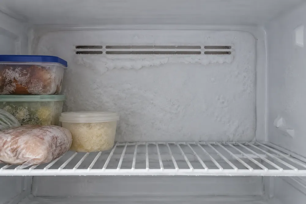 Frost covering a freezer's back panel with a thin ice ridge along the vent