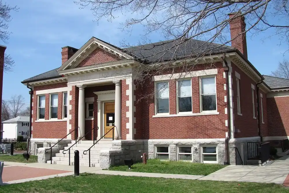 The brick Ashland Public Library with a stone stairway and lawn in Ashland, Massachusetts