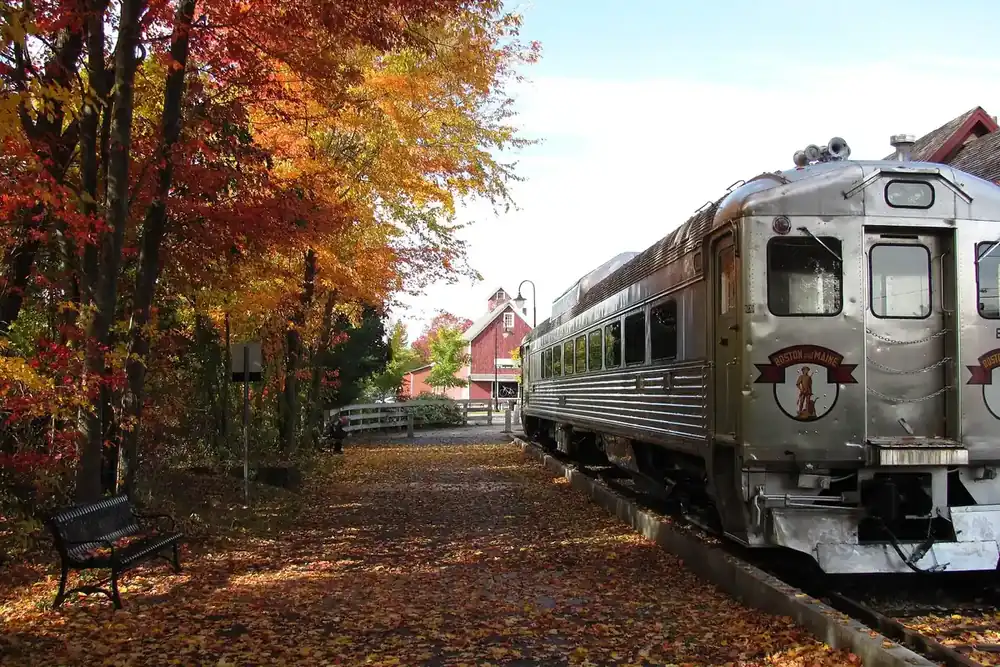 A vintage stainless rail car on the tracks beside autumn trees at Bedford Depot