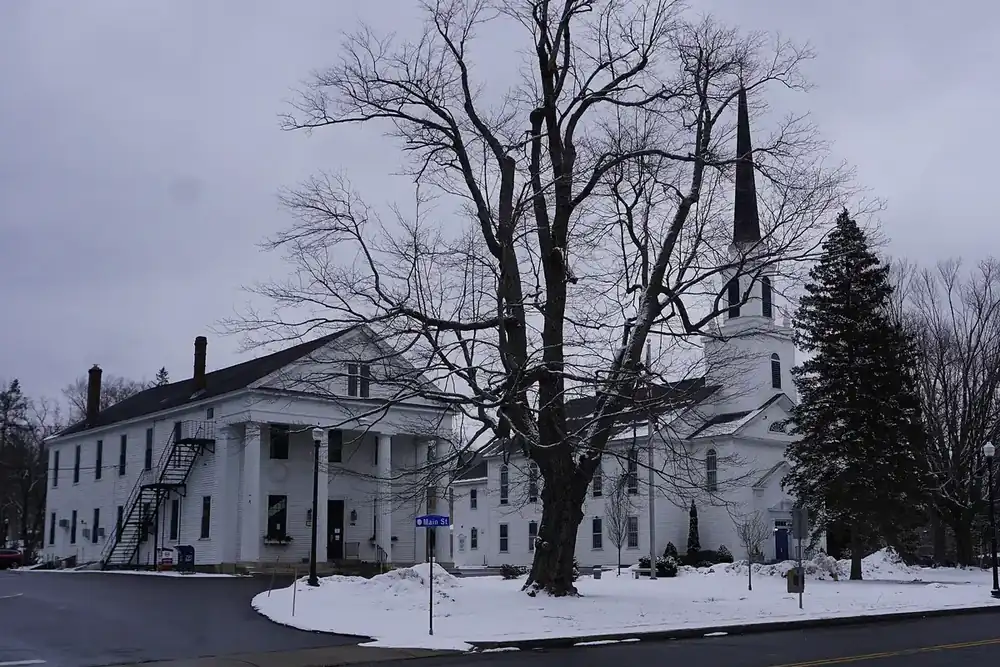 White colonial buildings and a church steeple around the snowy town center of Holden, Massachusetts