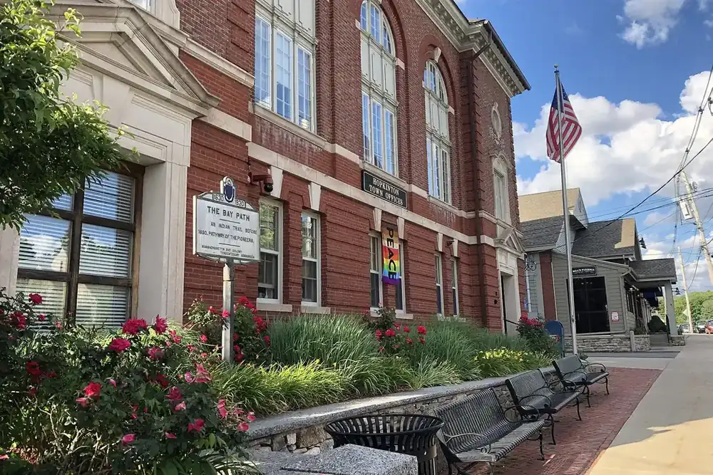 The brick Hopkinton Town Hall with flowers and benches along the sidewalk in Hopkinton