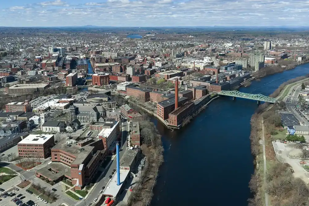 Aerial view of Lowell, Massachusetts, with brick mill buildings and a bridge along the river