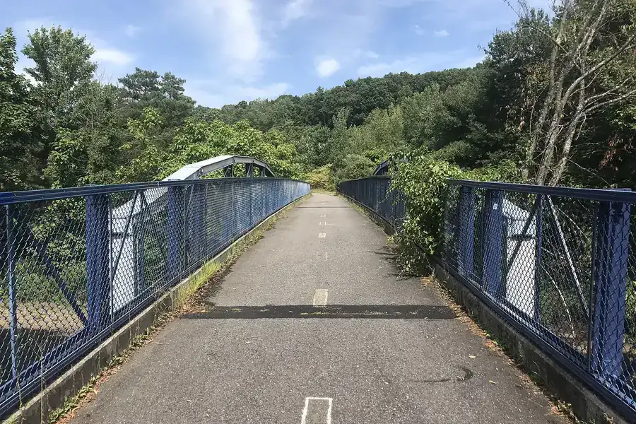A Blackstone River Bikeway bridge with blue railings crossing the river in Millbury