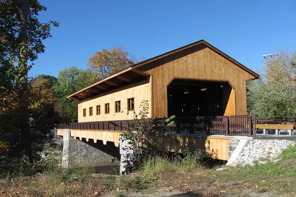 The timber Pepperell Covered Bridge crossing the Nashua River on a sunny fall day