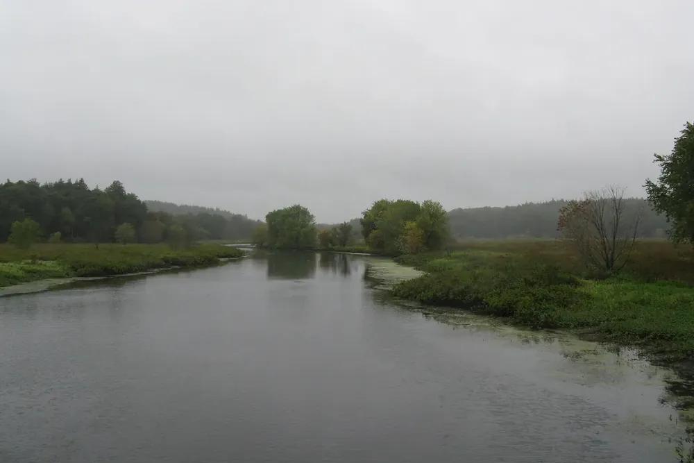 The Sudbury River winding through green marshland under a cloudy sky in Sudbury