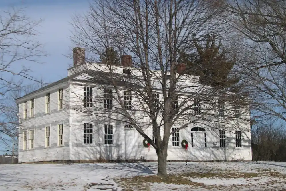 The white two-story Nathan Fisher House among bare trees in Westborough, Massachusetts